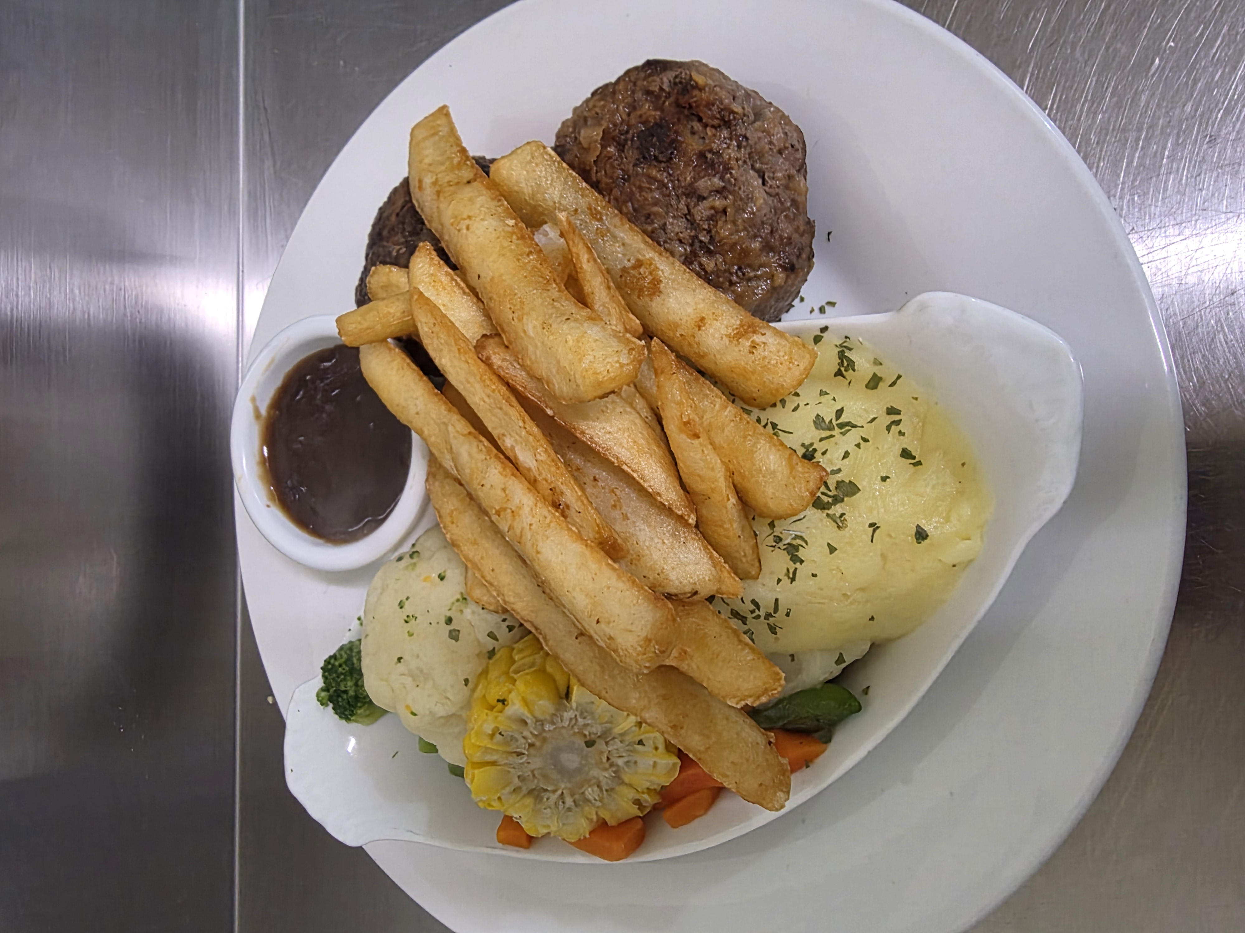 Homemade rissoles with chips, creamy mash, seasonal veggies and gravy